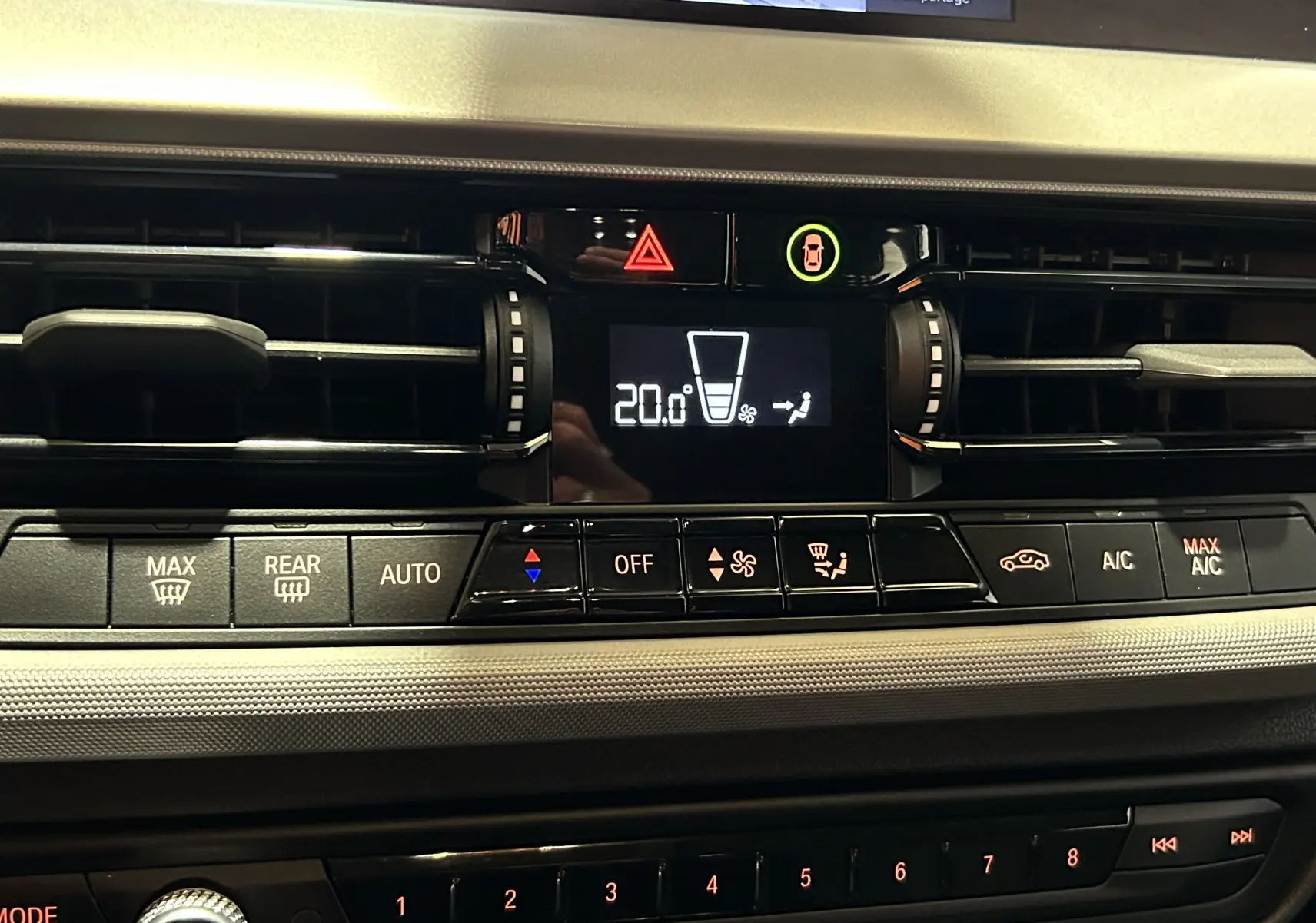 Gros plan sur la console centrale de la BMW Série 1 16d 2023, affichant la climatisation à 20°C avec commandes tactiles.