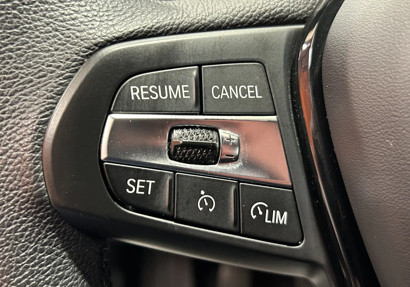 Gros plan sur les commandes de régulateur de vitesse au volant d'une BMW Série 1 noire de 2023.