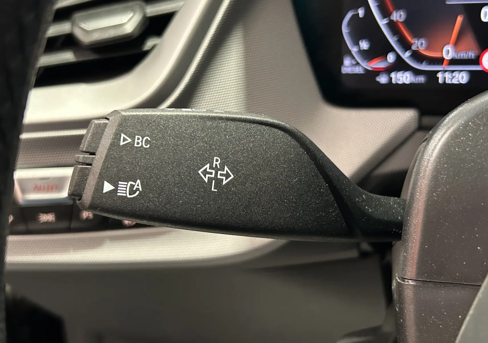 Gros plan sur la commande de clignotant gauche noire dans l'habitacle d'une BMW Série 1 noire 2023.