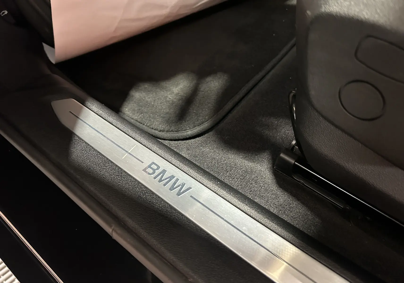 Gros plan sur la plaque de seuil de porte BMW dans l'habitacle d'une Série 1 noire 2023 côté gauche.