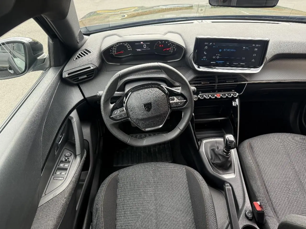 Vue intérieure frontale du Peugeot 2008 2025 noir perla, avec volant compact, tableau de bord numérique et boîte manuelle.