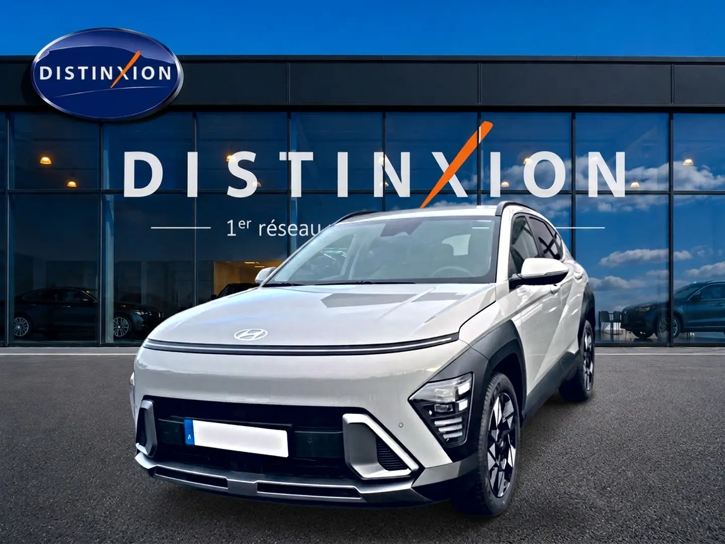 Hyundai Kona hybride gris en 3/4 avant droit, avec jantes alliage et calandre épurée devant un showroom Distinxion.