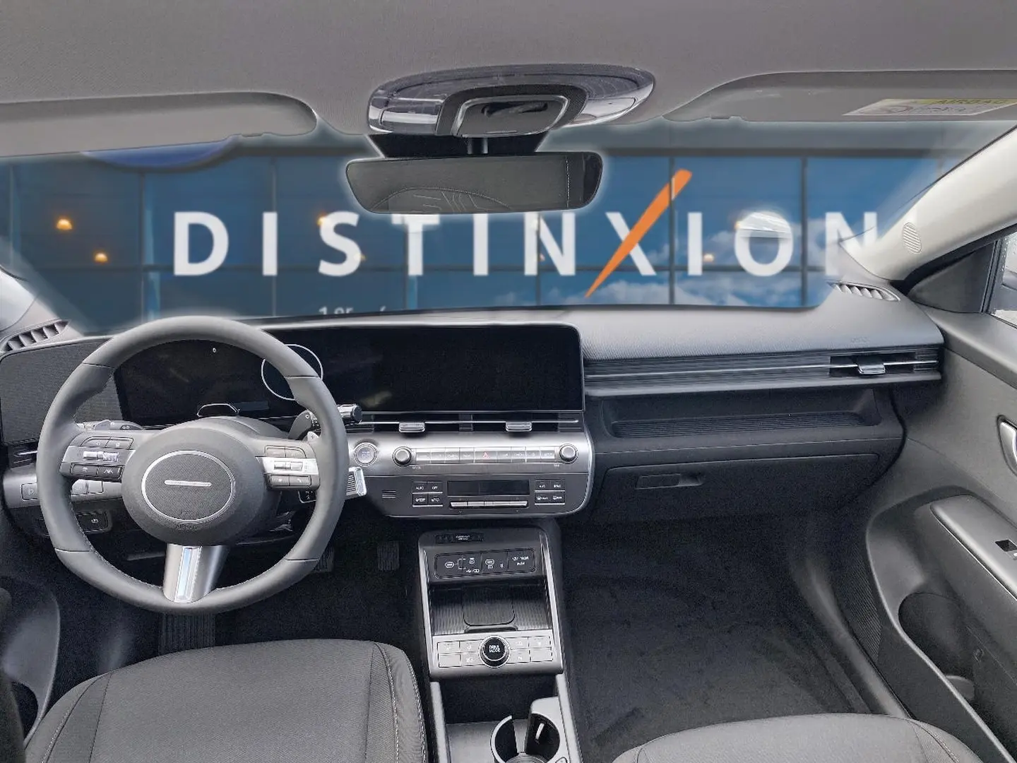 Vue intérieure avant du Hyundai Kona gris 2025, mettant en valeur le tableau de bord moderne et le volant multifonction cuir.