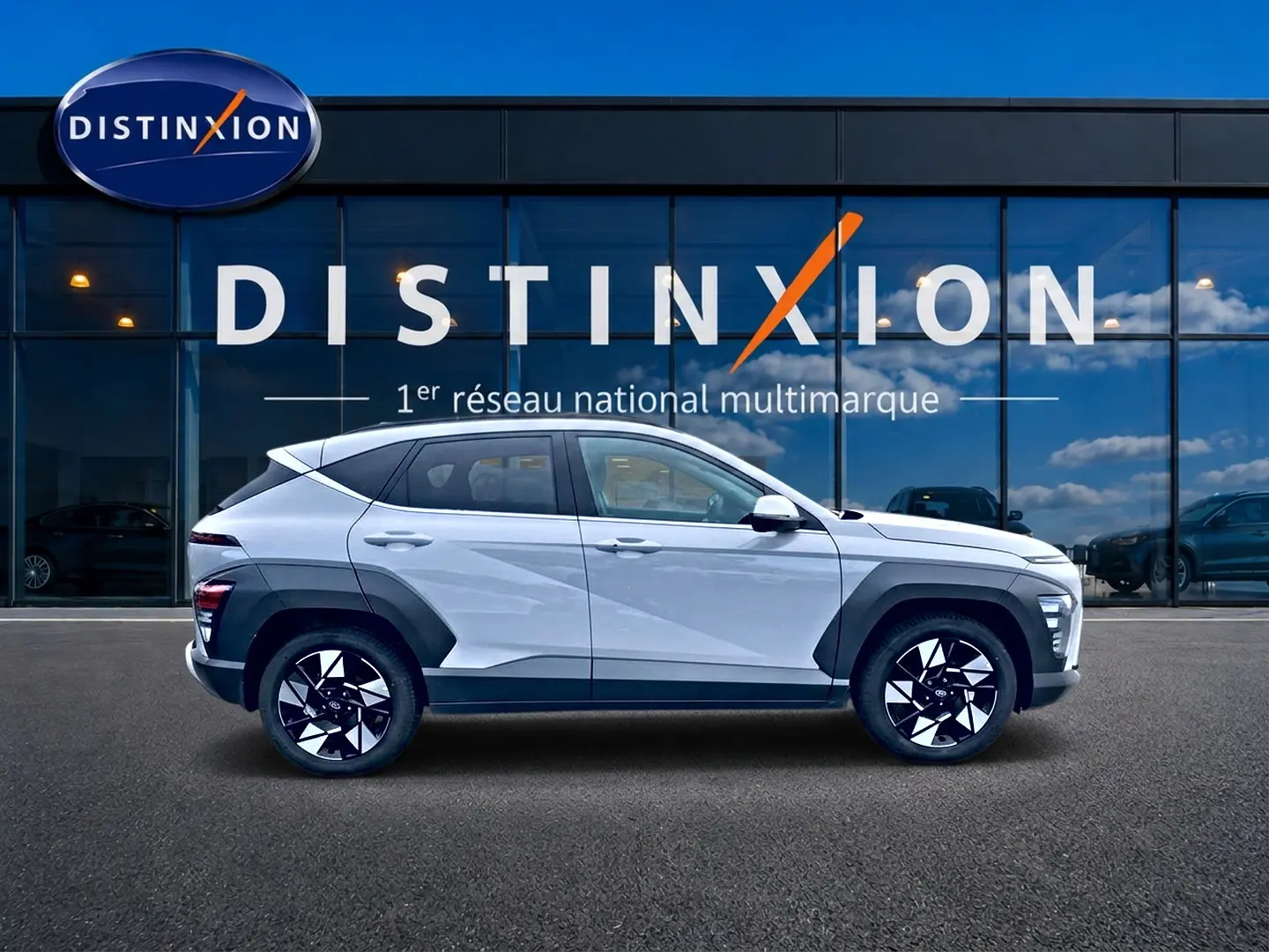Vue latérale droite d'un Hyundai Kona gris 2025 avec protections noires et jantes alliage au design géométrique.