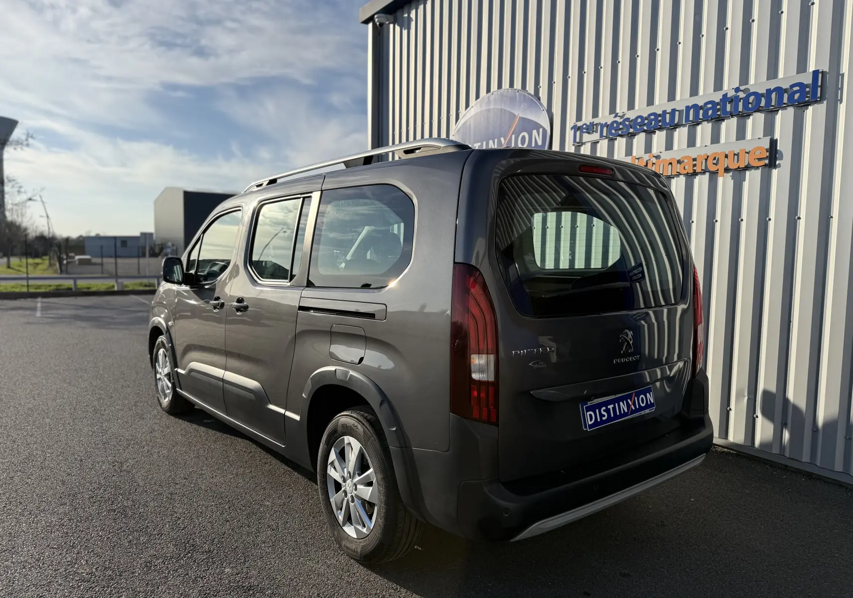 Vue 3/4 arrière droite d’un Peugeot Rifter gris platinium 2020, avec hayon et vitres latérales teintées.