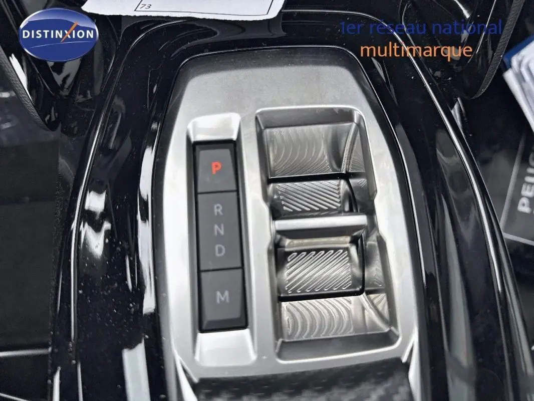 Gros plan sur la console centrale noire du Peugeot 2008 1.2 Hybrid 145ch avec sélecteur de boîte auto et boutons de mode.