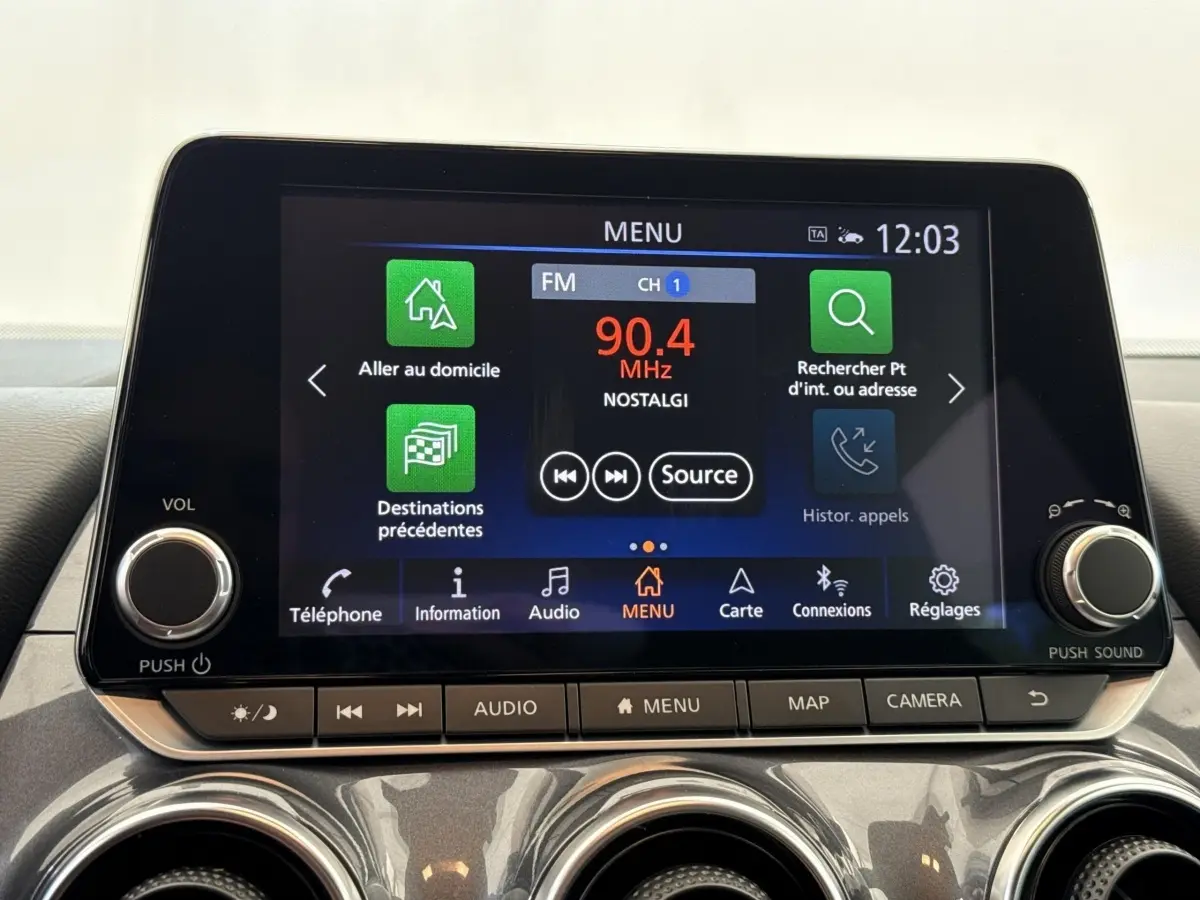 Écran tactile central du tableau de bord du Nissan Juke 2023, affichant le menu radio et navigation.