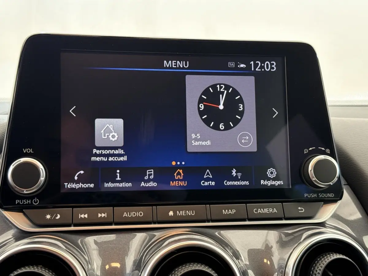Écran tactile central du tableau de bord du Nissan Juke 2023, affichant l'horloge et le menu principal.