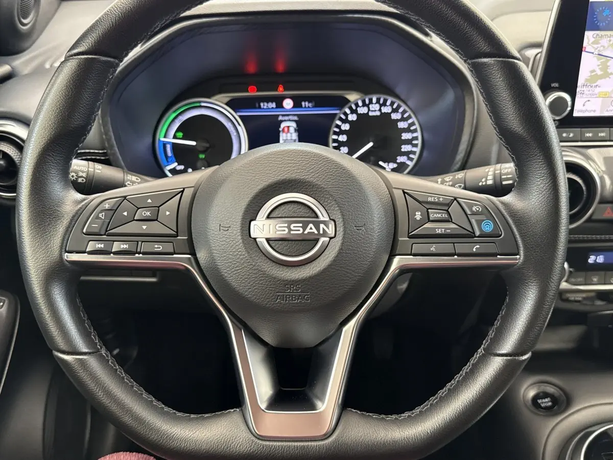 Vue rapprochée du volant noir d’un Nissan Juke 2023 avec tableau de bord numérique et écran tactile de navigation visible à droite.