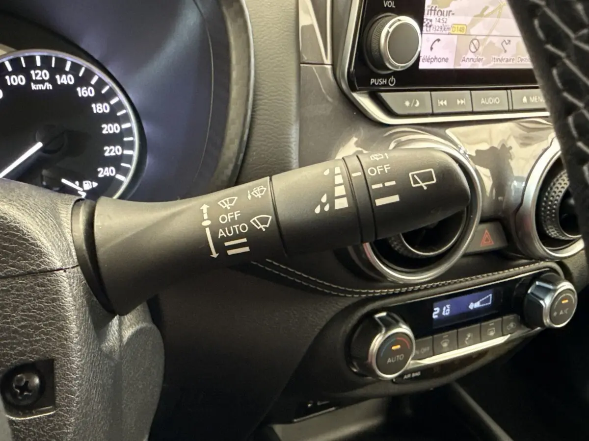 Gros plan sur la commande d’essuie-glace et le tableau de bord noir du Nissan Juke 2023 essence hybride.