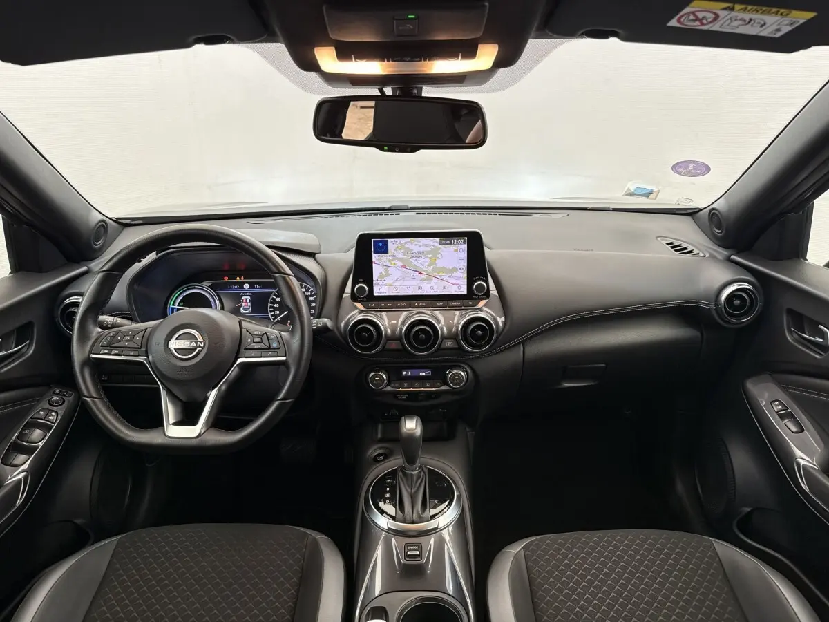 Vue intérieure avant du tableau de bord gris foncé du Nissan Juke 2023 avec écran tactile central et volant multifonctions.
