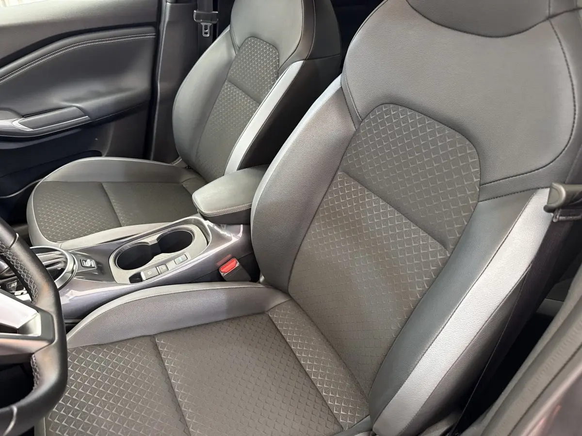 Vue intérieure rapprochée des sièges avant gris foncé du Nissan Juke 2023, avec console centrale et accoudoir visible.