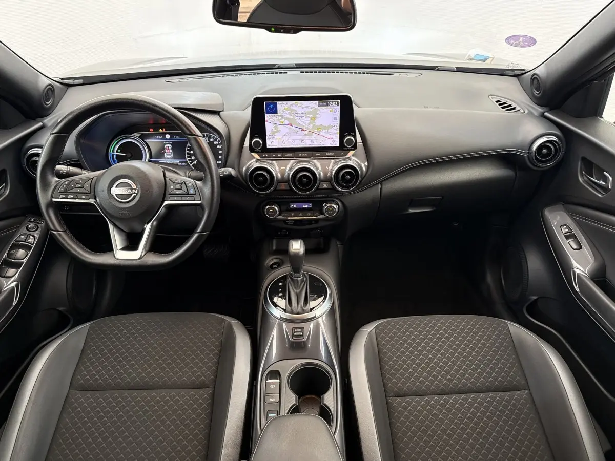 Intérieur avant du Nissan Juke 2023 gris foncé, vue centrée sur le tableau de bord avec écran tactile et volant multifonctions.