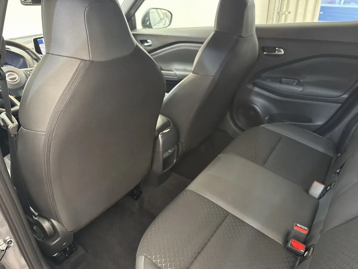 Vue intérieure arrière du Nissan Juke 2023 gris foncé, montrant la banquette 3 places et les dossiers des sièges avant en tissu noir.