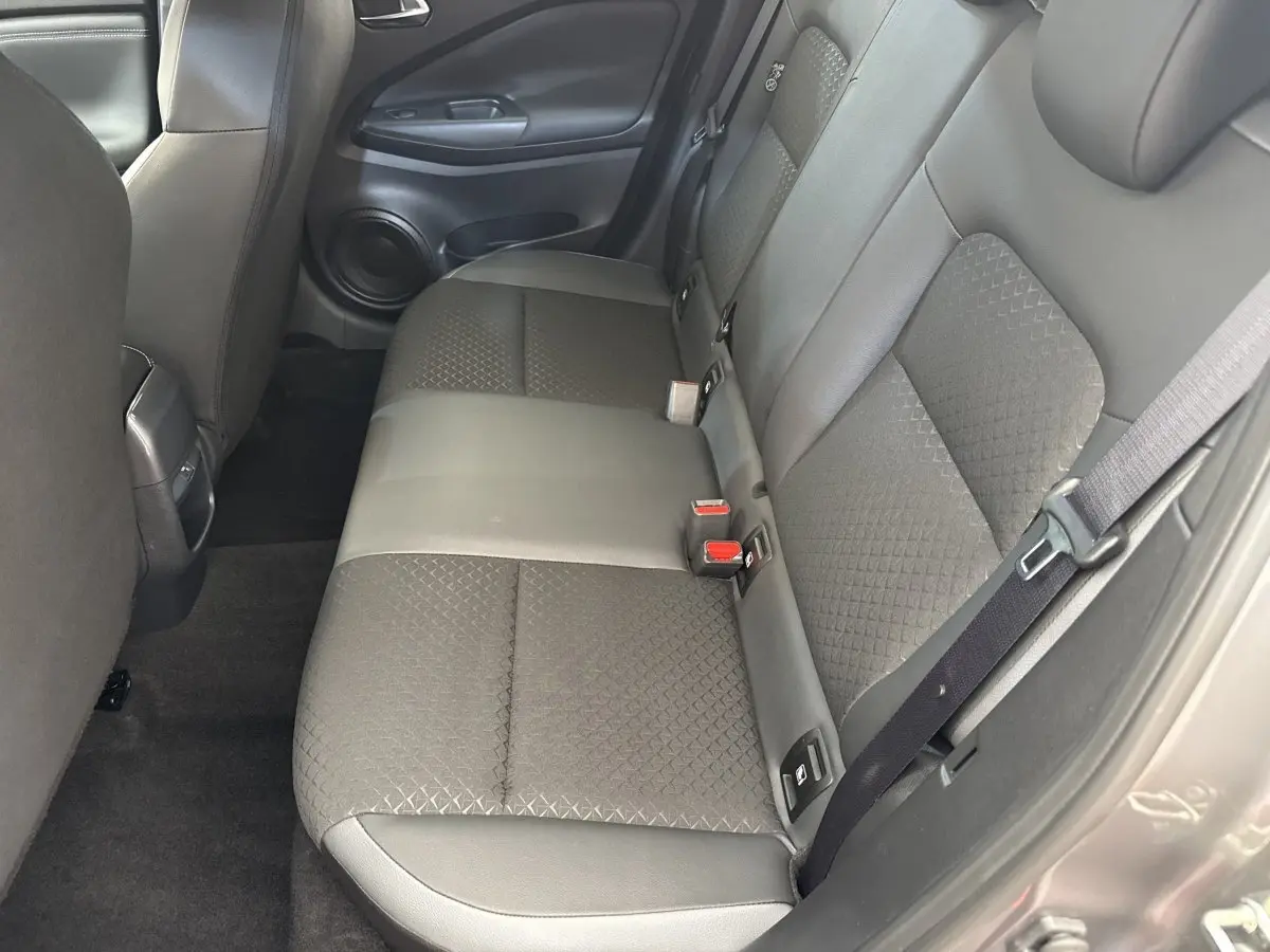 Vue intérieure côté droit montrant la banquette arrière gris foncé du Nissan Juke 2023 avec ceinture de sécurité attachée.