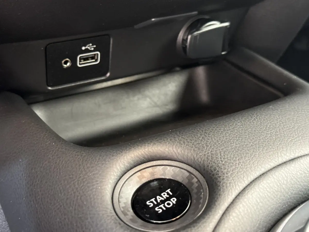 Gros plan sur le bouton Start Stop entouré d’un cerclage effet carbone dans l’habitacle du Nissan Juke 2023.