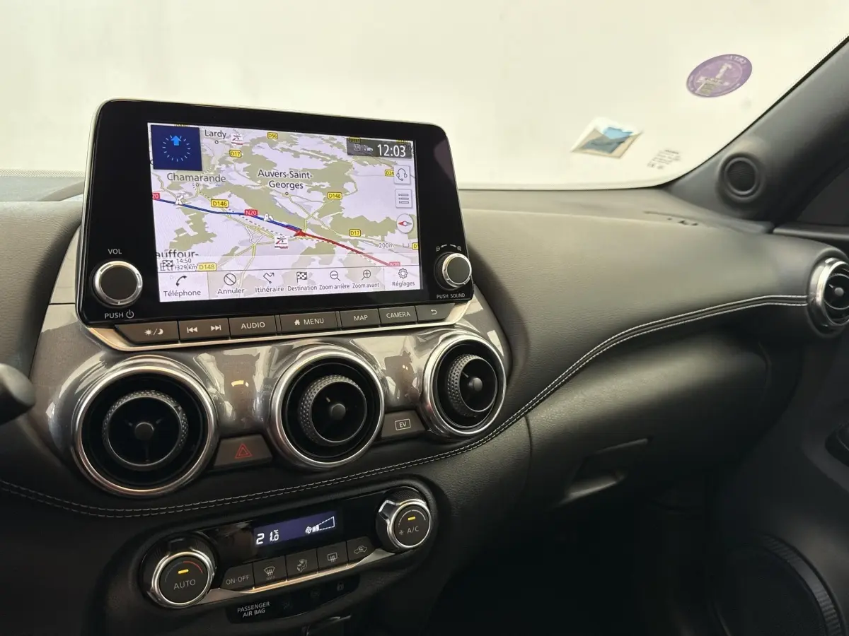 Vue intérieure du tableau de bord du Nissan Juke gris foncé 2023 avec écran tactile de navigation et aérateurs ronds.