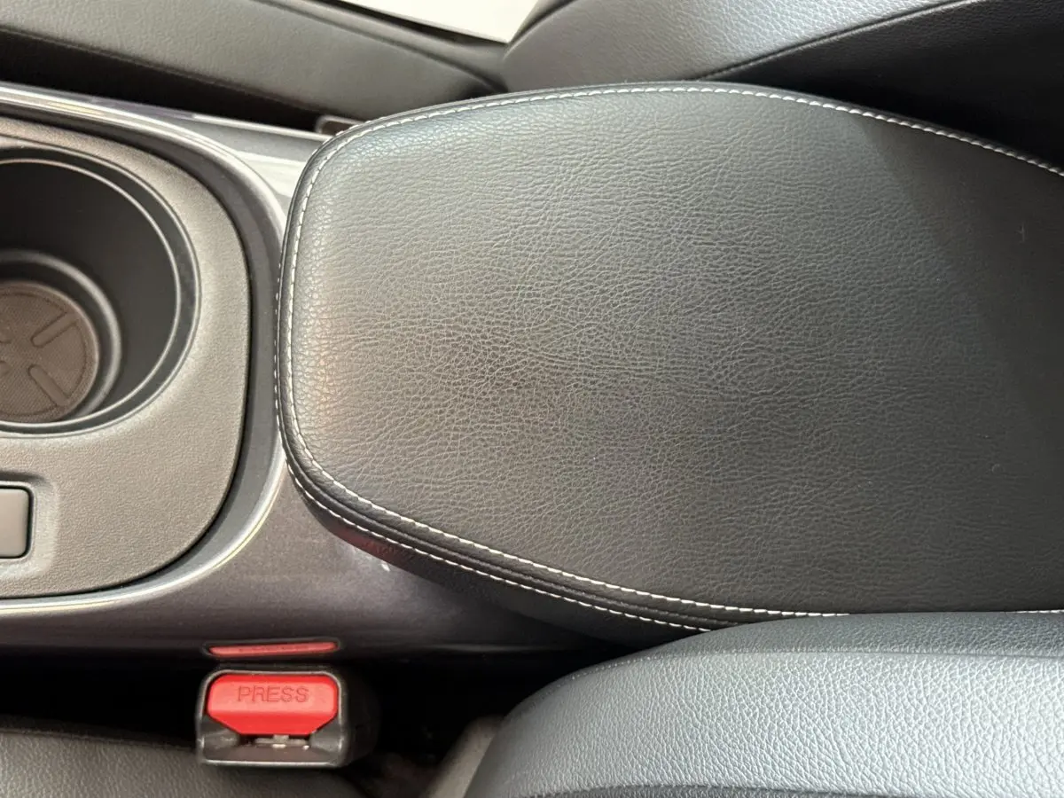Détail de l'accoudoir central en cuir noir avec surpiqûres blanches dans l'habitacle du Nissan Juke 2023.