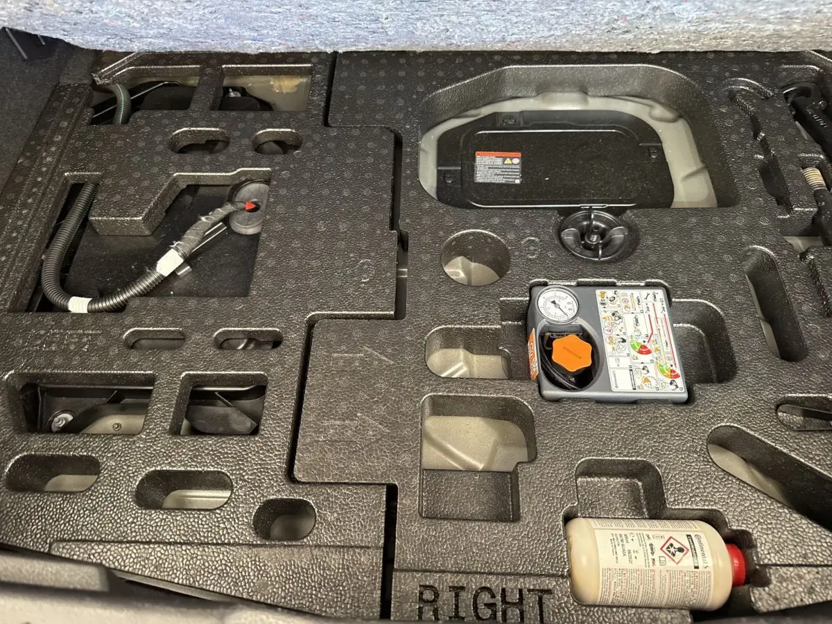 Vue rapprochée du coffre du Nissan Juke 2023 gris foncé, montrant le rangement mousse et le kit de réparation pneus.