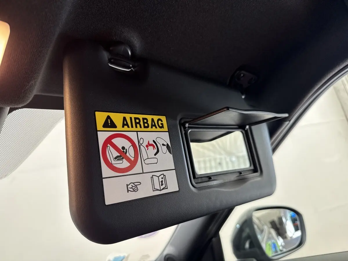 Détail du pare-soleil côté conducteur avec miroir et avertissement airbag dans un Nissan Juke gris foncé 2023.