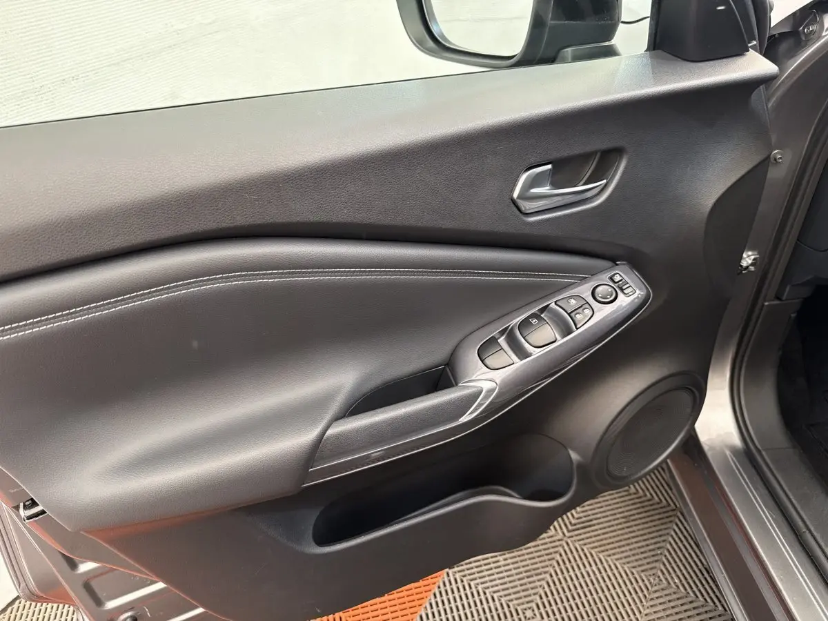 Vue intérieure côté conducteur de la porte gris foncé du Nissan Juke 2023 avec commandes électriques et haut-parleur intégré.
