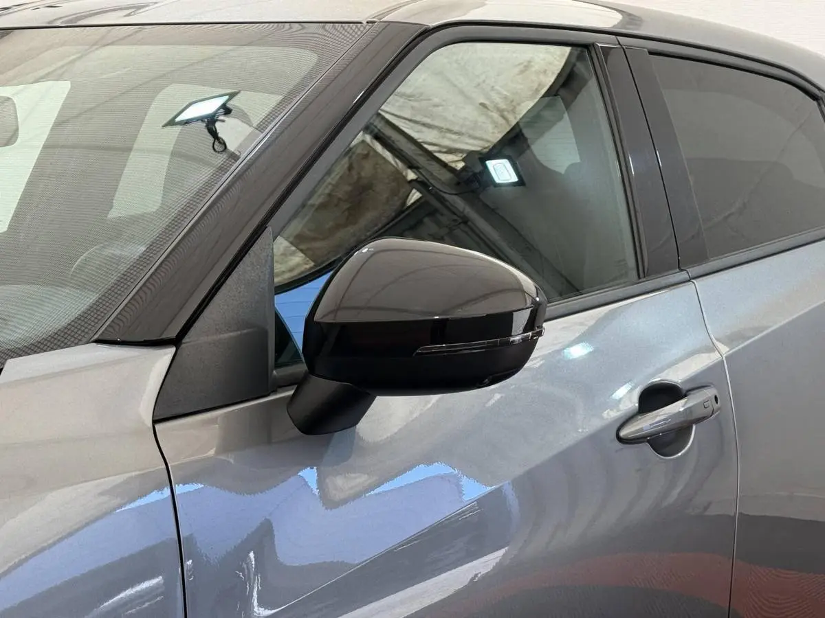 Gros plan sur le rétroviseur noir et la porte côté gauche d’un Nissan Juke gris foncé 2023.