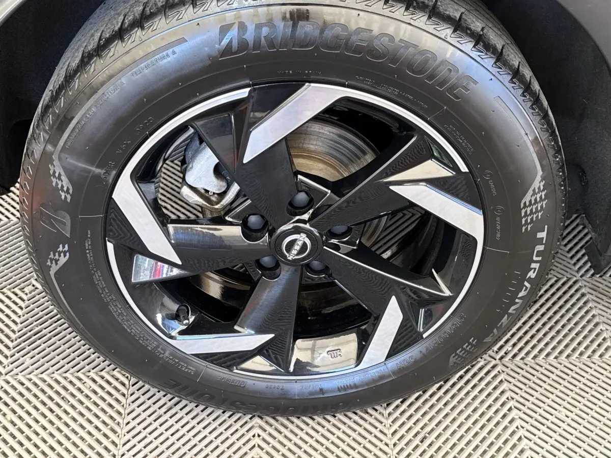 Gros plan sur la roue avant droite du Nissan Juke 2023 gris foncé, jante alliage noir et argent avec pneu Bridgestone.