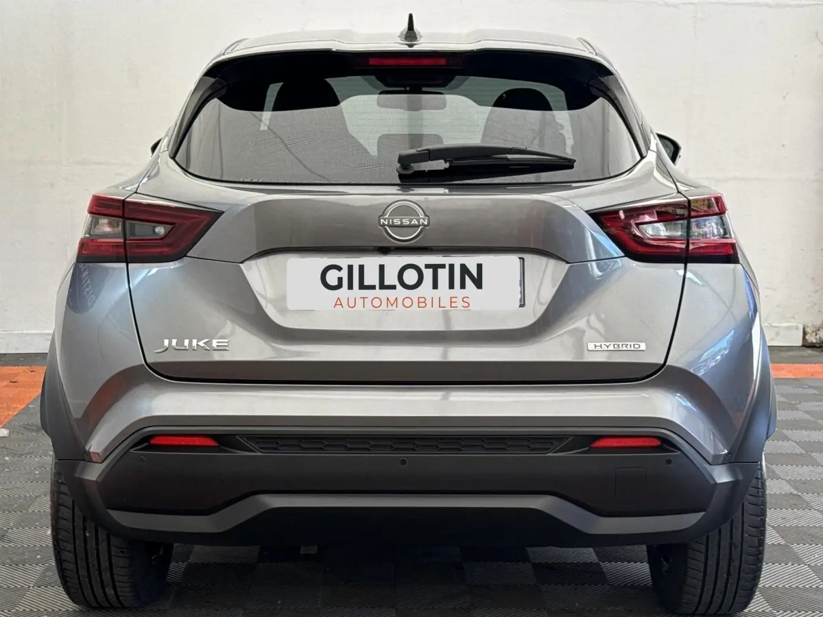 Vue arrière d'un Nissan Juke gris foncé 2023 hybride, avec feux LED et logo distinctif sur le hayon.