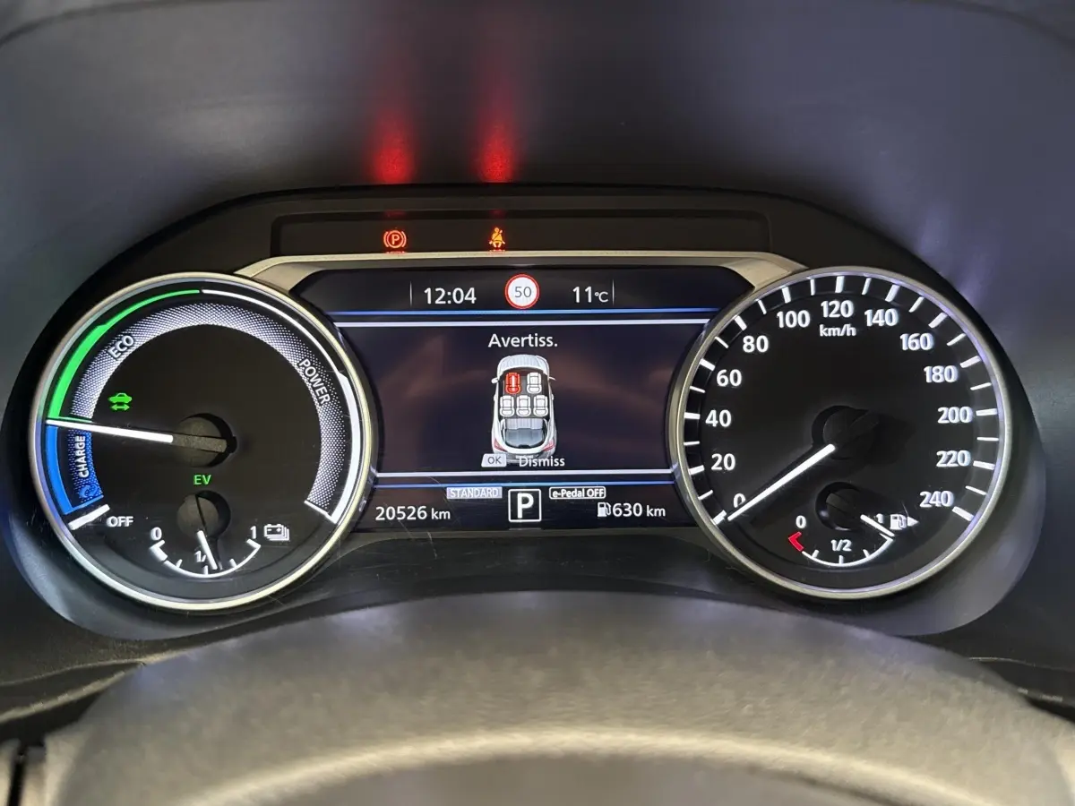 Vue rapprochée du tableau de bord numérique du Nissan Juke 2023, affichant la vitesse, autonomie et avertissements.