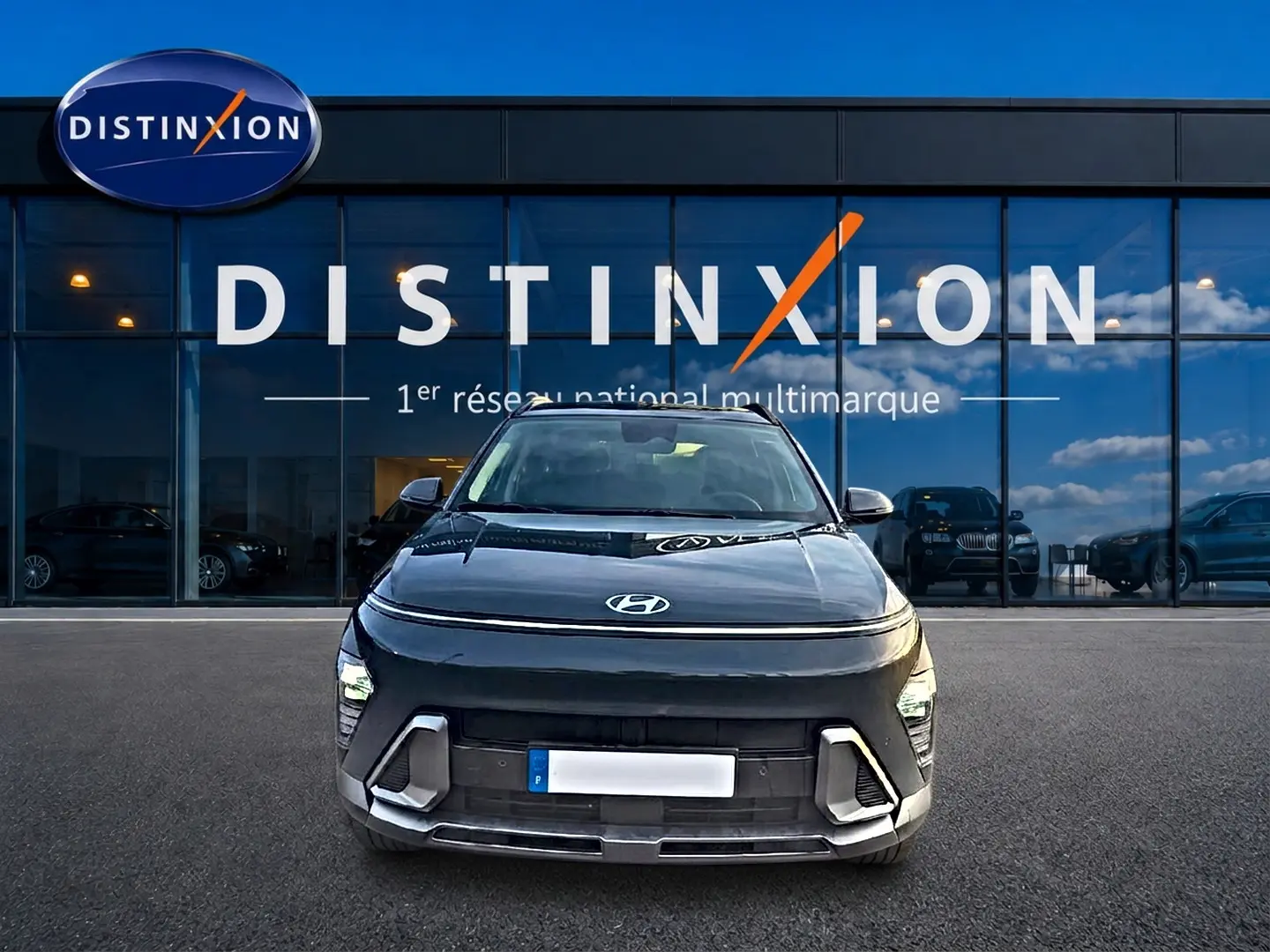 Vue frontale d'une Hyundai Kona 2025 gris ecotronic devant une vitrine Distinxion, avec feux LED et calandre moderne.