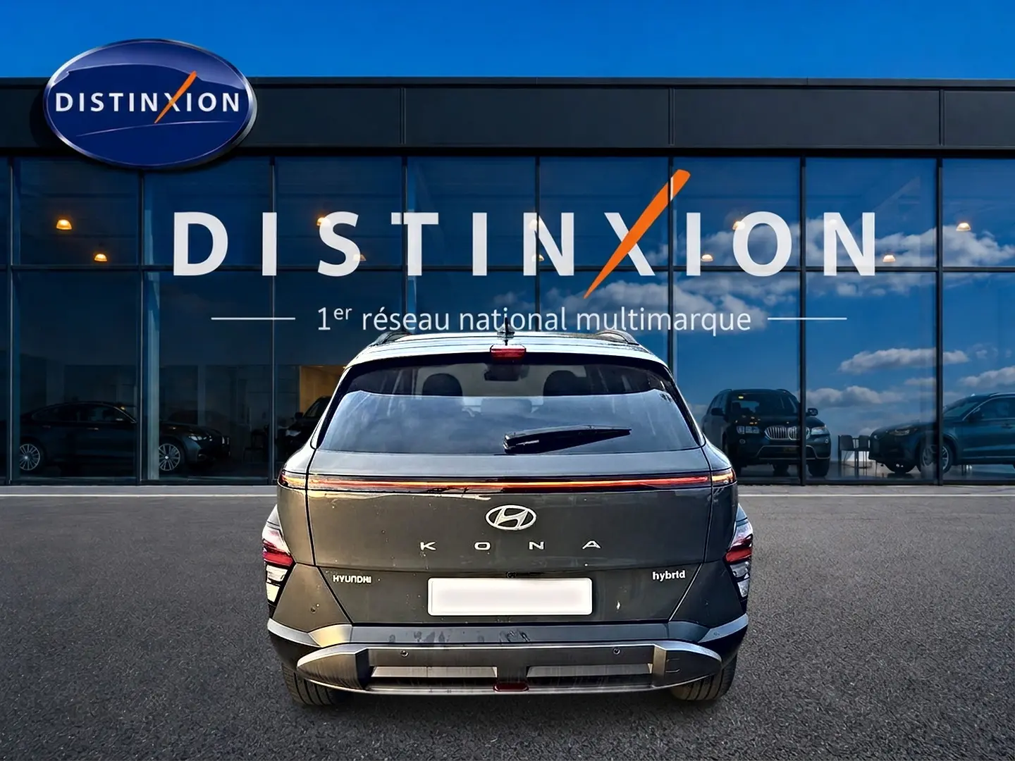 Vue arrière d’un Hyundai Kona hybride gris ecotronic, avec feux LED et logo Hyundai visible devant un showroom Distinxion.