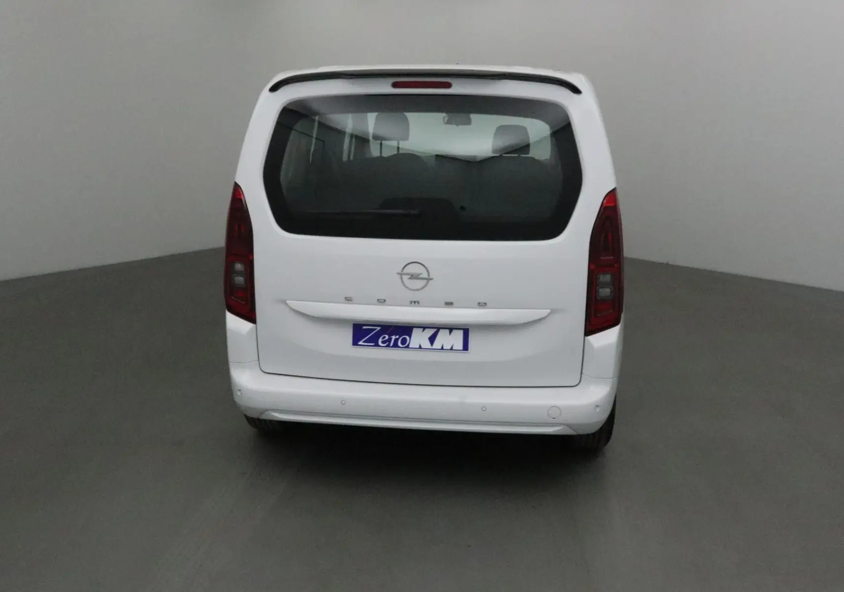 Vue arrière d'un Opel Combo Life blanc avec hayon vitré et becquet arrière dans un studio neutre.