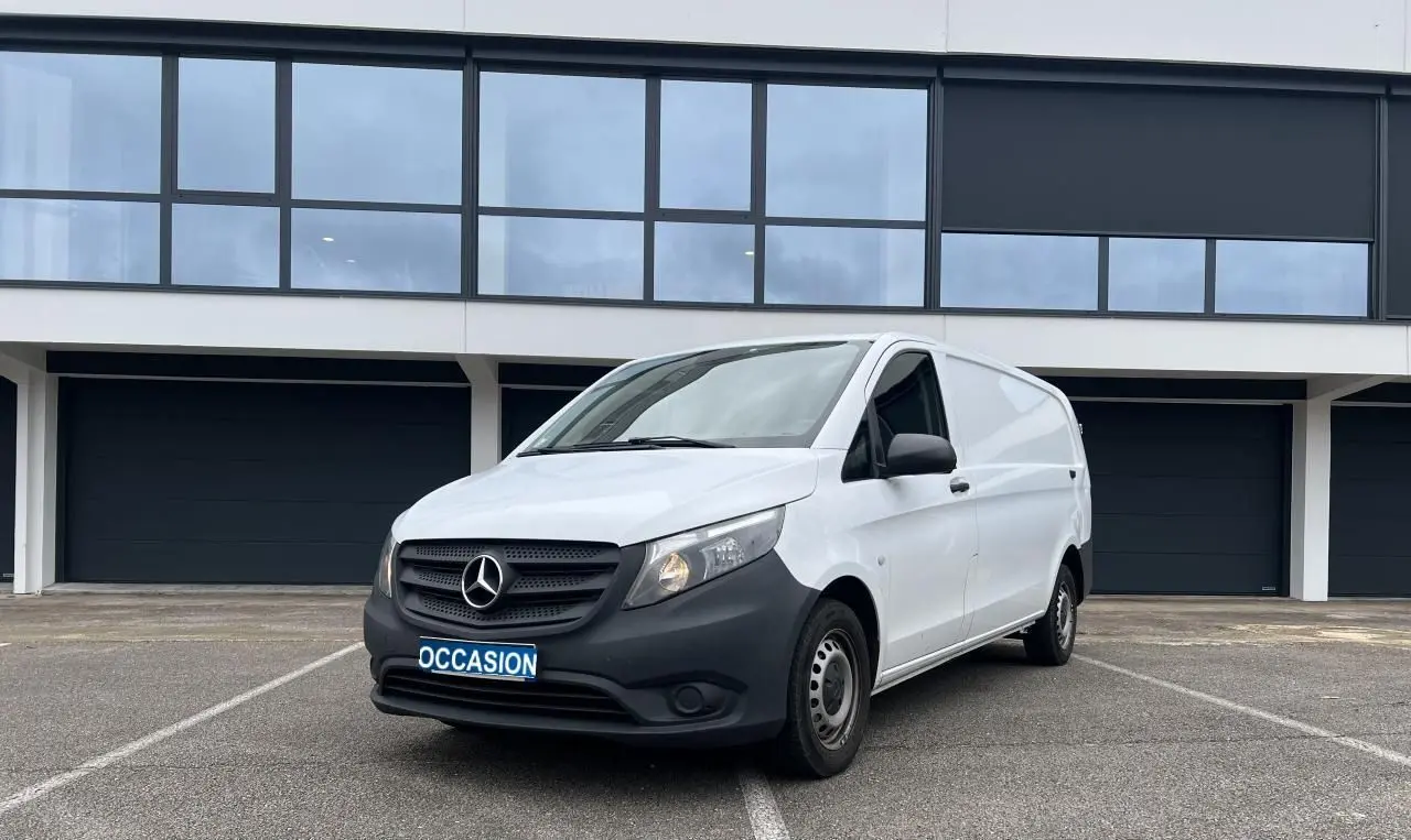 Vue 3/4 avant droit d’un Mercedes Vito Fourgon blanc avec pare-chocs noir et plaque "OCCASION" sur parking.