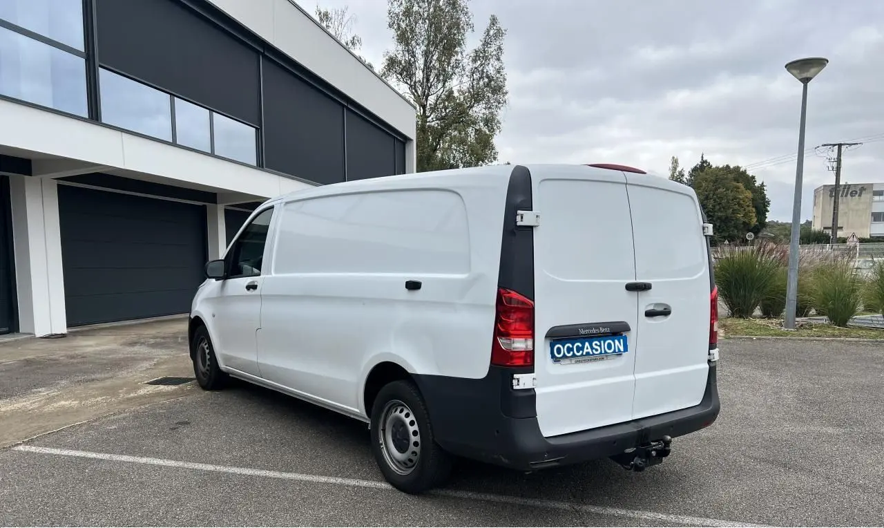 Vue 3/4 arrière droite d’un Mercedes Vito Fourgon blanc avec attelage et porte latérale, stationné en extérieur.
