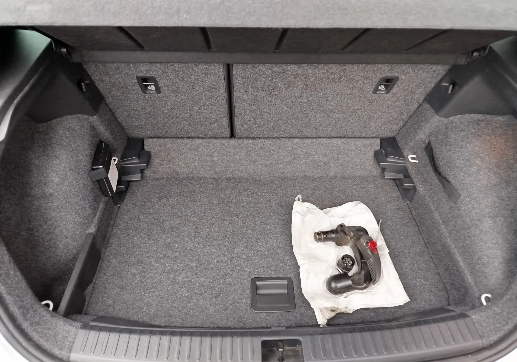Coffre ouvert d'un SEAT Arona blanc avec toit gris, vue plongeante sur l'espace de chargement et un attelage posé.