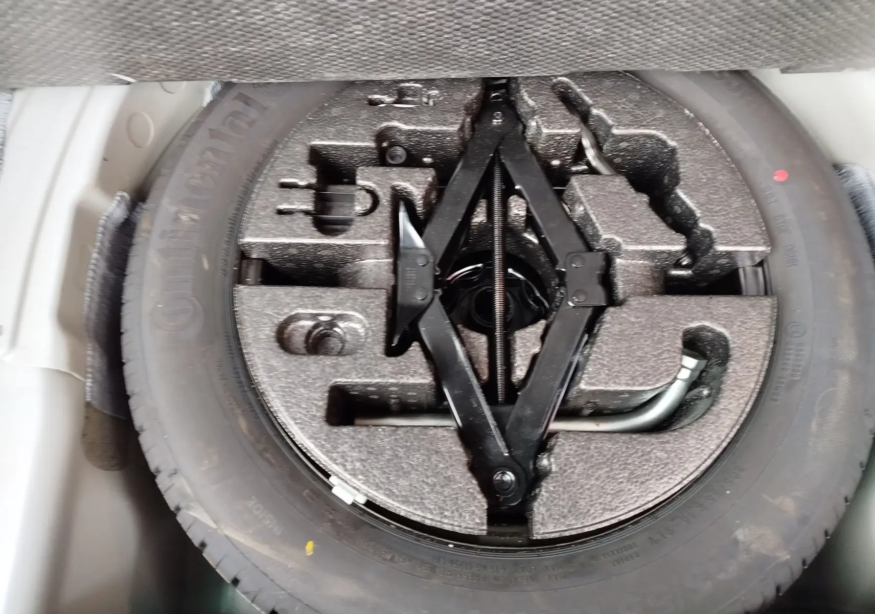 Gros plan sur la roue de secours et le cric noir dans le coffre d’un SEAT Arona blanc avec toit gris.