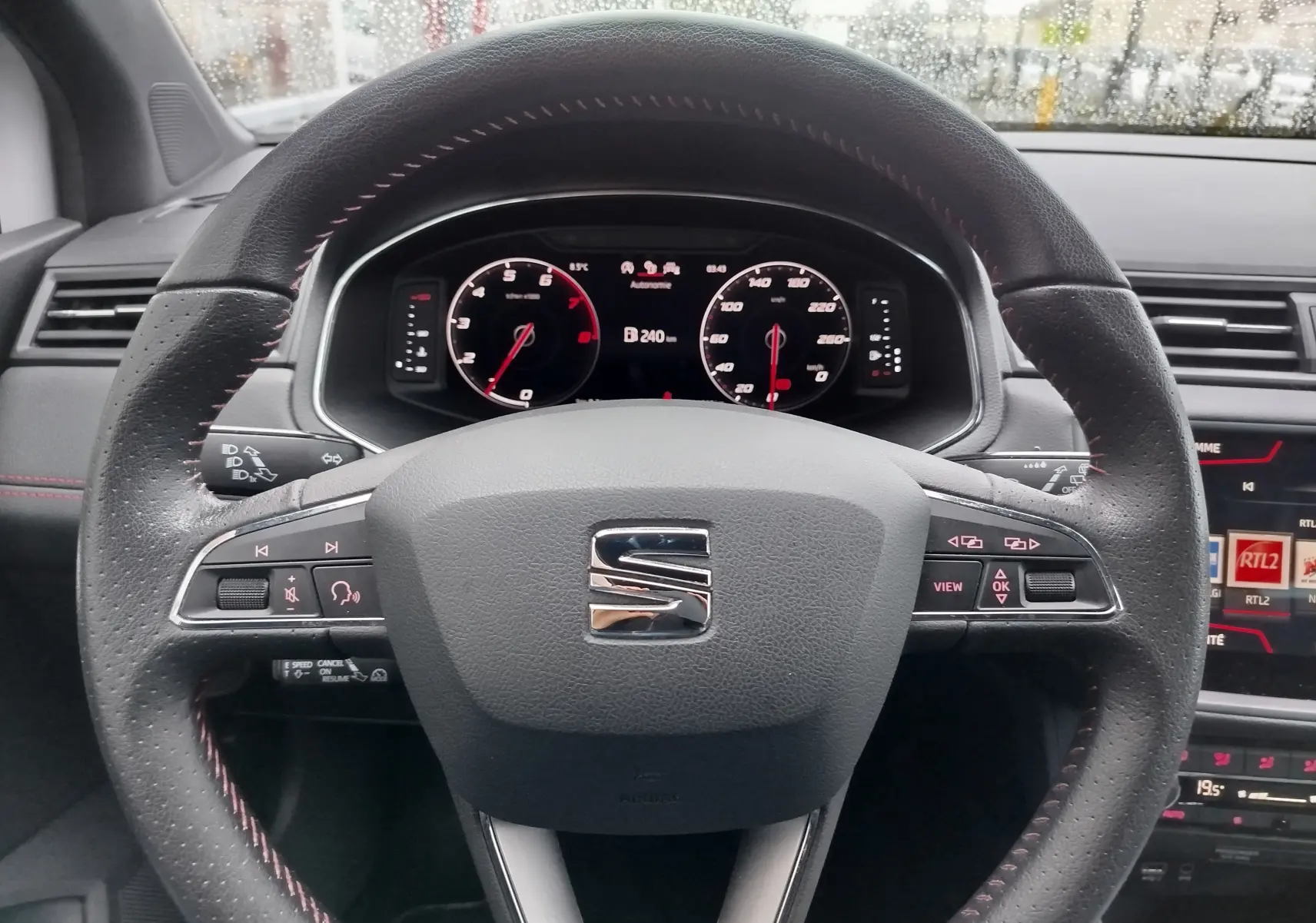 Vue rapprochée du volant en cuir noir avec surpiqûres rouges du tableau de bord d'une SEAT Arona 2020.