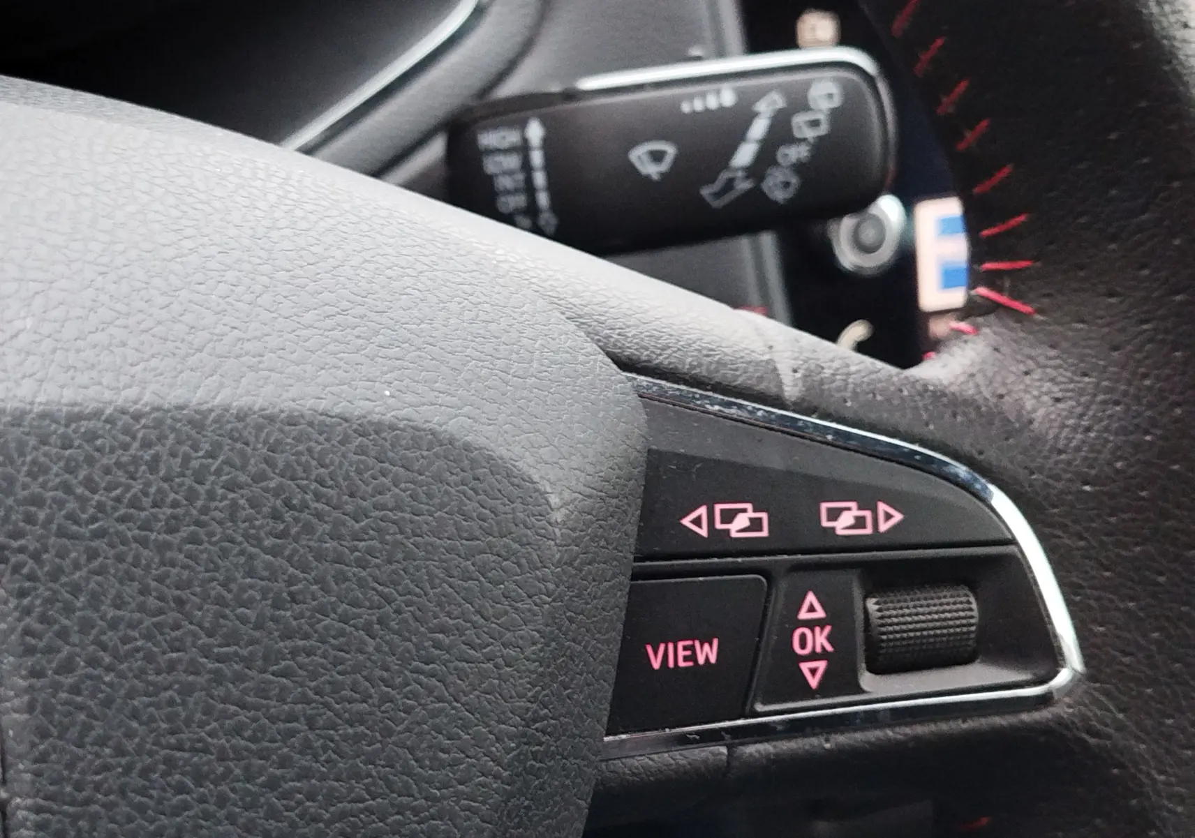 Gros plan sur les commandes au volant noir avec surpiqûres rouges du SEAT Arona blanc, version FR 2020.