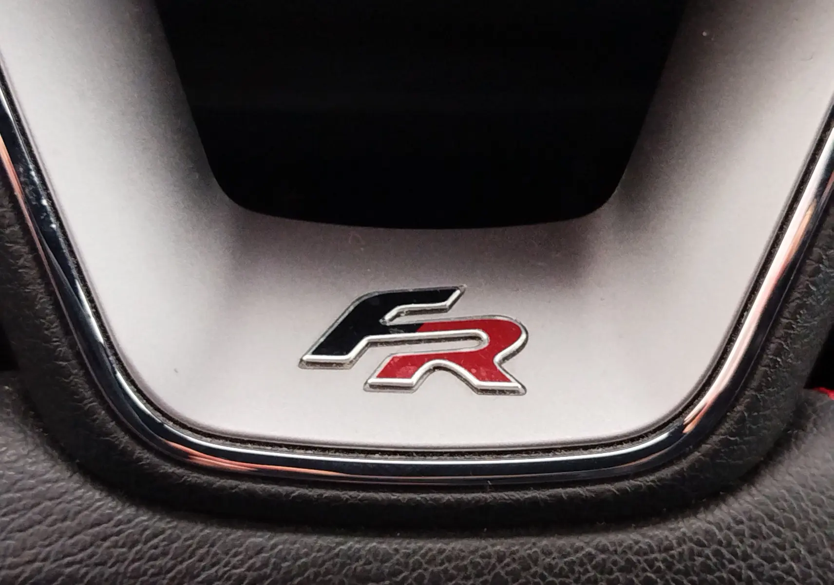 Gros plan sur le logo FR bicolore noir et rouge sur le volant d'une SEAT ARONA 2020 finition FR.