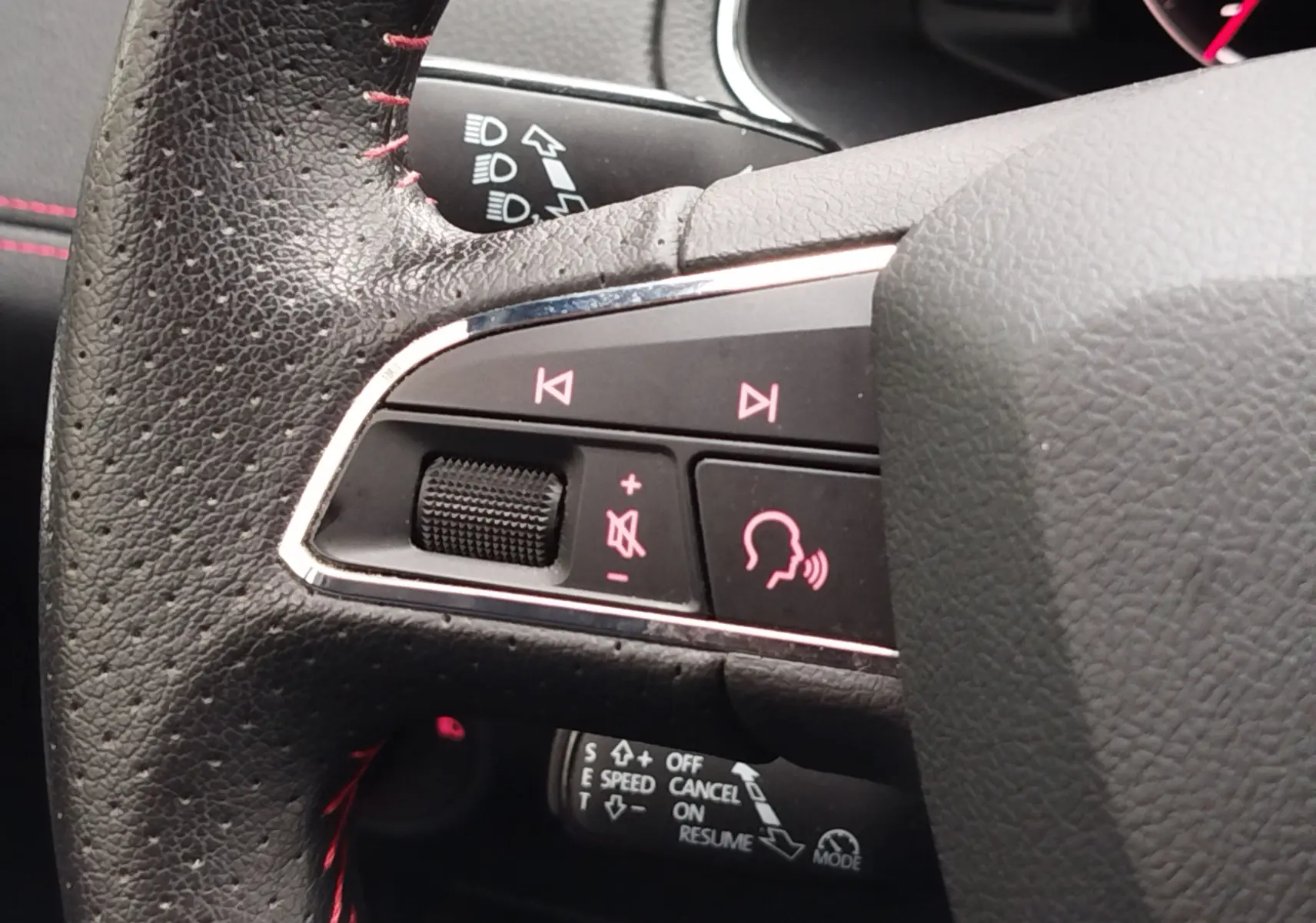 Gros plan sur les commandes audio et vocales au volant en cuir noir avec surpiqûres rouges du SEAT Arona 2020.