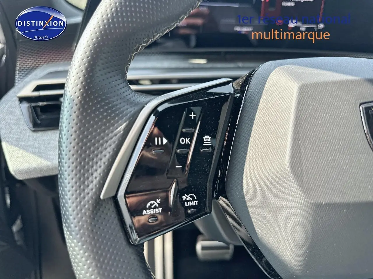 Gros plan sur le volant cuir perforé de la Peugeot 3008 gris Artense, avec commandes multifonctions visibles à gauche.