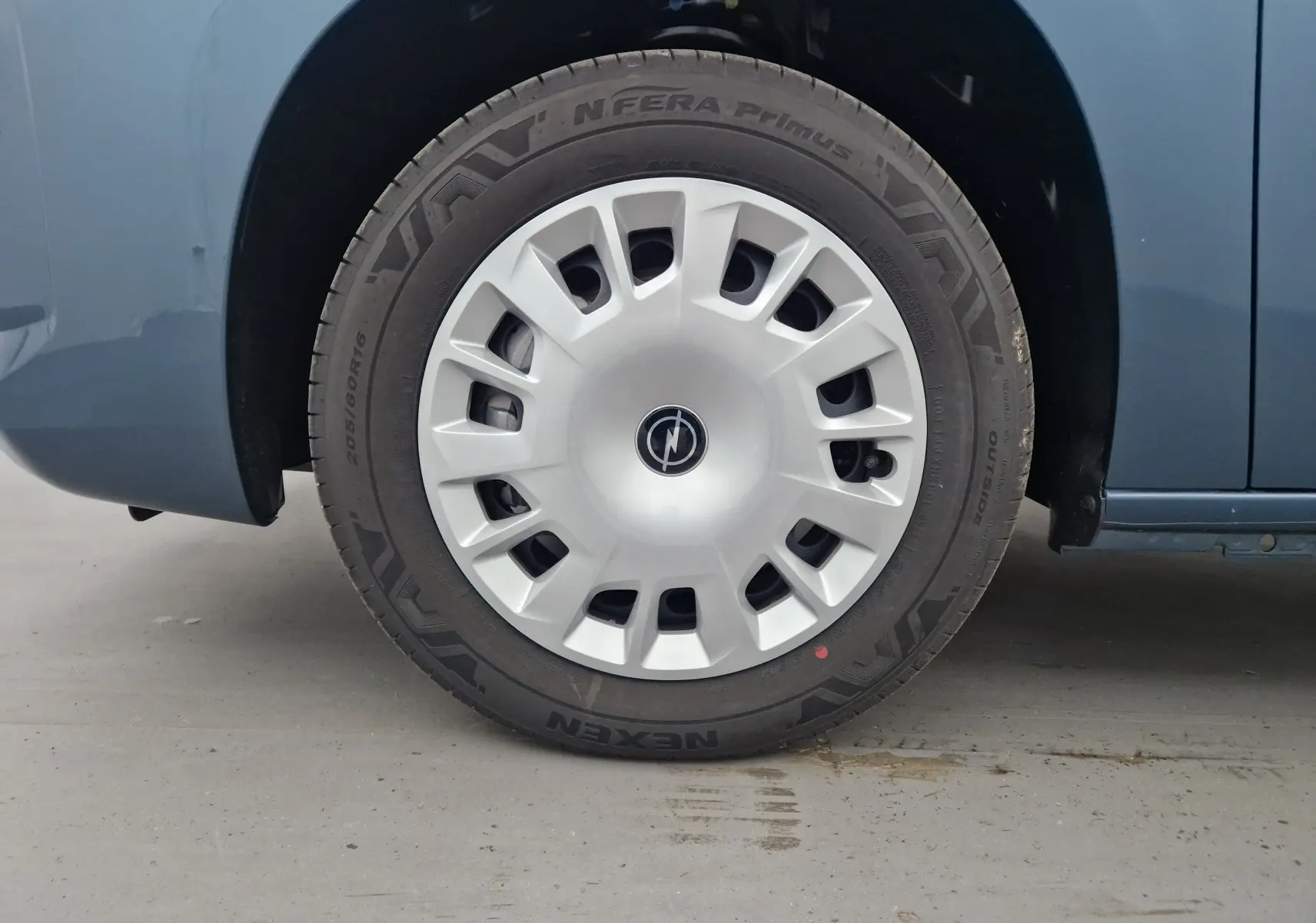 Gros plan sur la roue avant gauche bleu Kiama de l'Opel Combo Life 2025 avec enjoliveur argenté au design moderne.