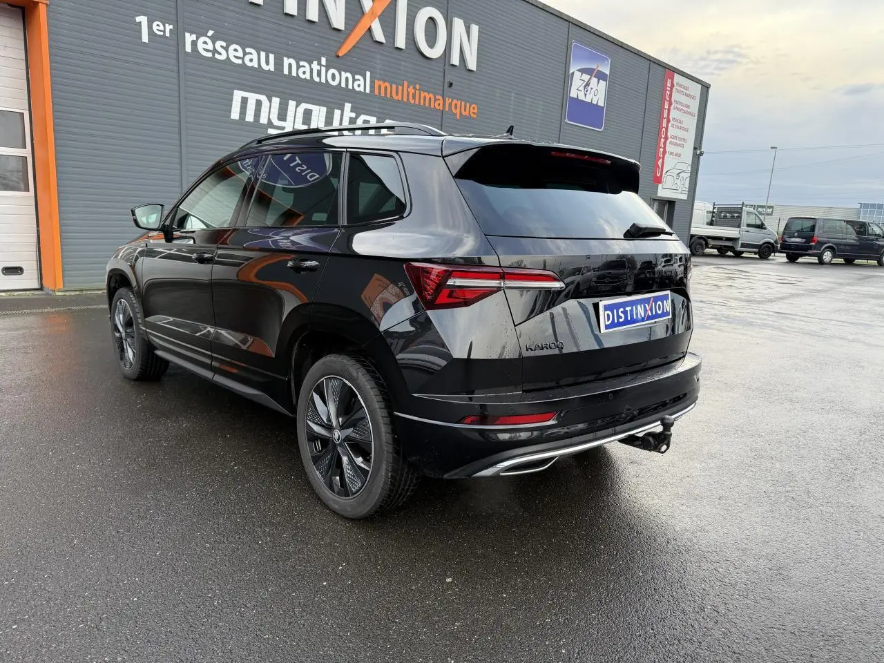 Vue 3/4 arrière droite d'un Skoda Karoq noir magic nacré avec crochet d'attelage et jantes alliage noires.