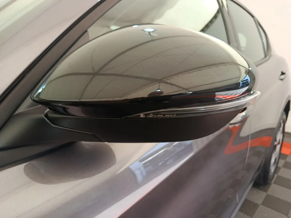 Rétroviseur droit noir brillant avec clignotant intégré sur Alfa Romeo Stelvio gris foncé vue rapprochée côté droit.