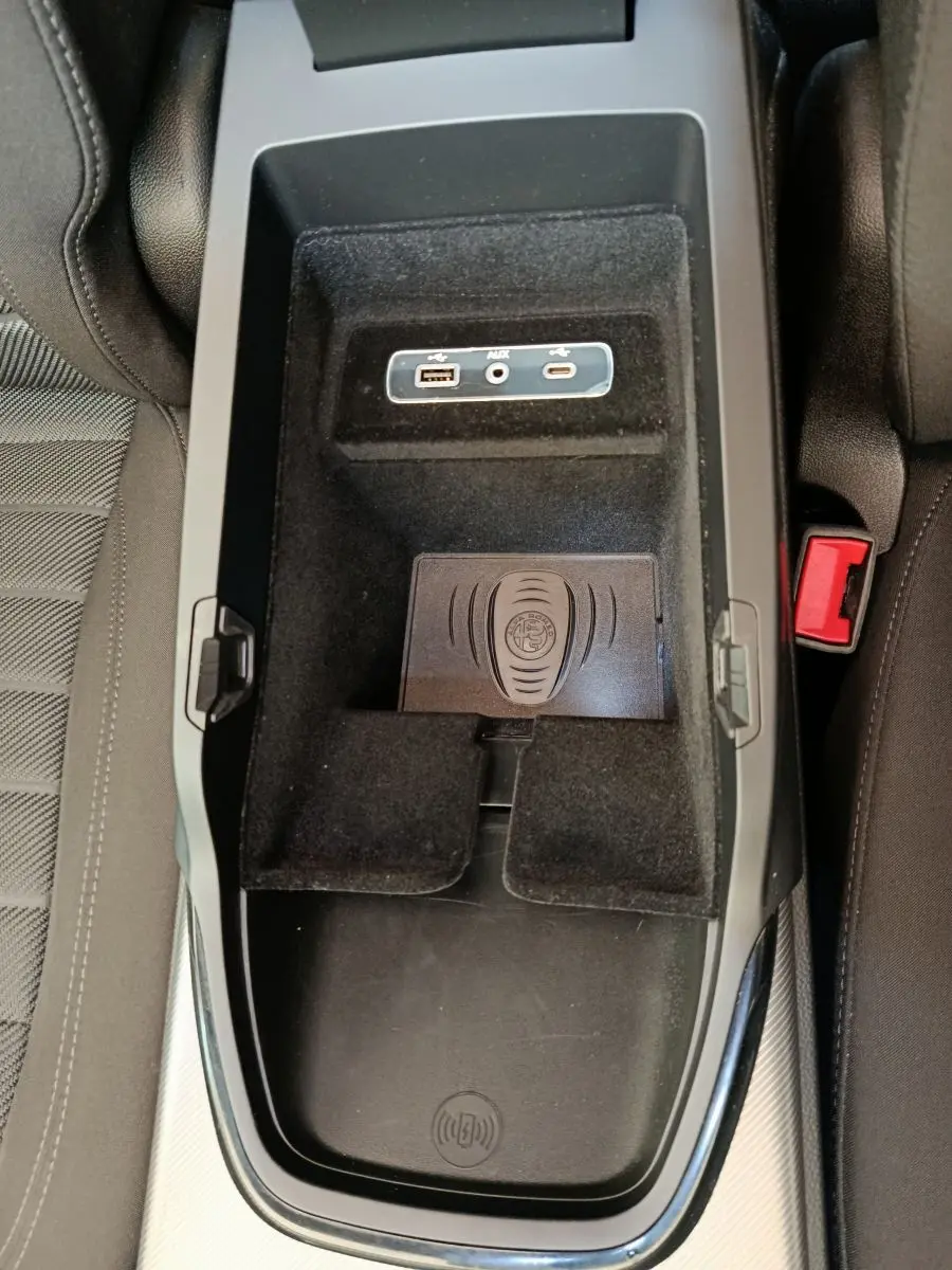 Vue plongeante sur la console centrale noire de l'Alfa Romeo Stelvio gris foncé, avec ports USB et tapis de recharge à induction.