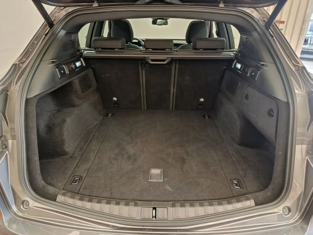 Coffre ouvert vu de l'arrière d'un Alfa Romeo Stelvio gris foncé, intérieur spacieux et tapis noir.
