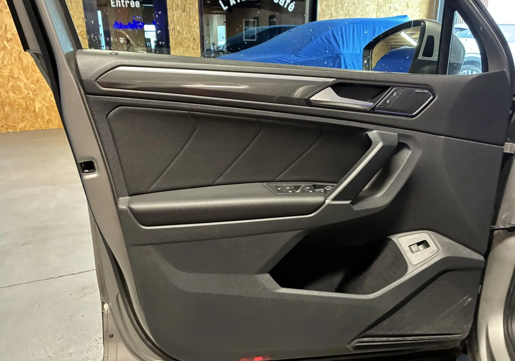 Vue intérieure côté gauche de la porte avant gris foncé du Volkswagen Tiguan 2.0 TDI 2017 avec commandes électriques.