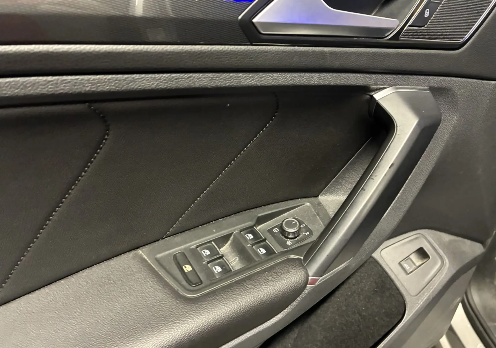 Détail de la porte côté conducteur du Volkswagen Tiguan gris 2017, avec commandes électriques des vitres et rétroviseurs.
