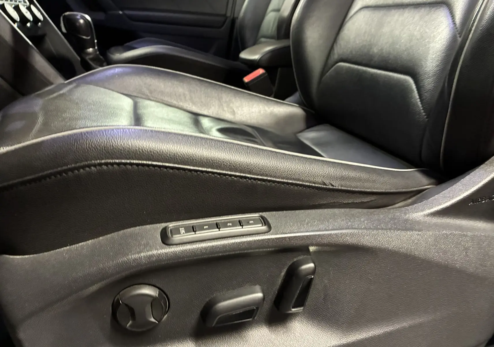 Gros plan sur le siège conducteur en cuir noir du Volkswagen Tiguan 2.0 TDI 150 Carat, avec commandes électriques visibles sur le côté.