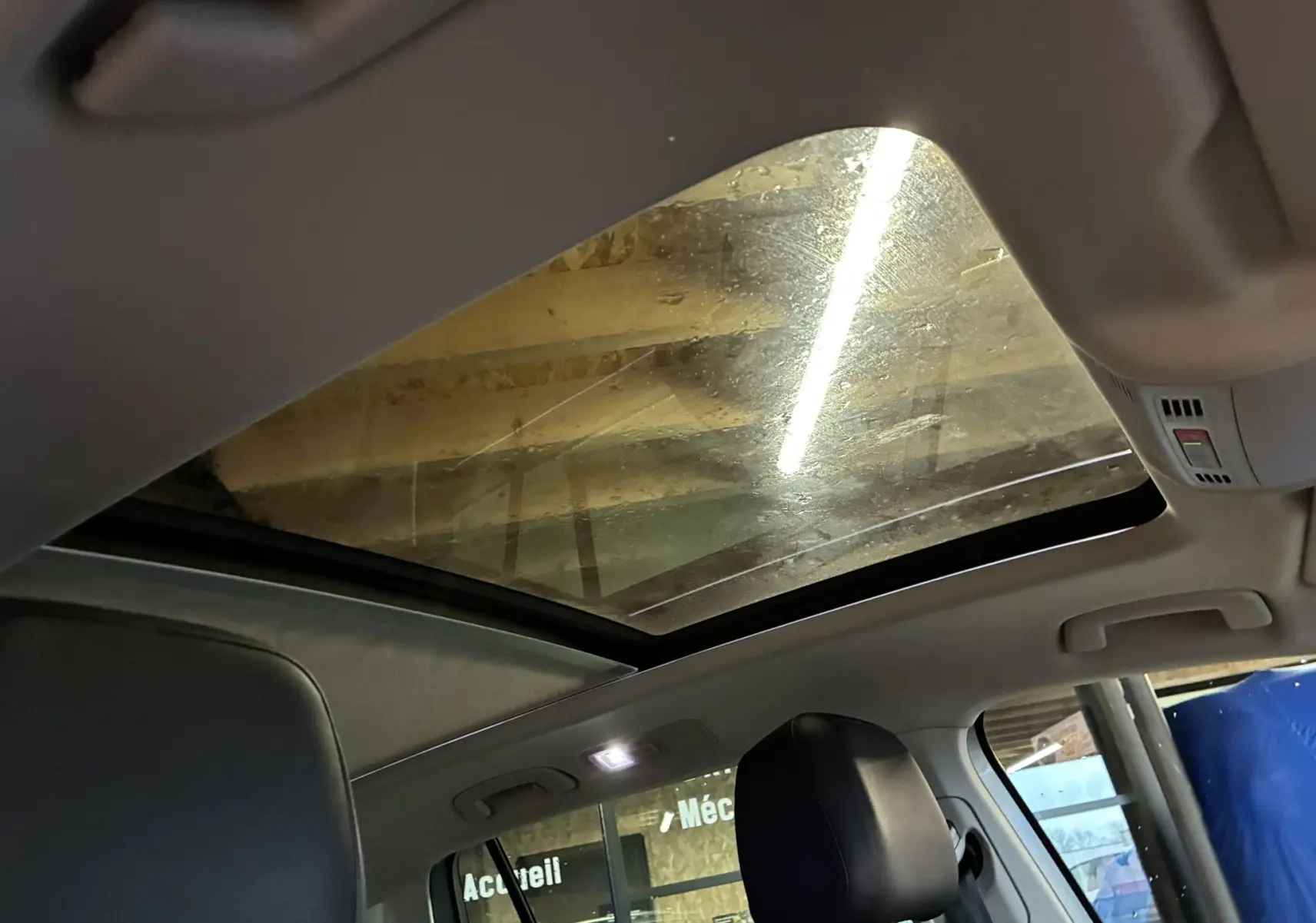 Vue intérieure du toit ouvrant panoramique du Volkswagen Tiguan gris, avec siège avant en cuir noir visible.